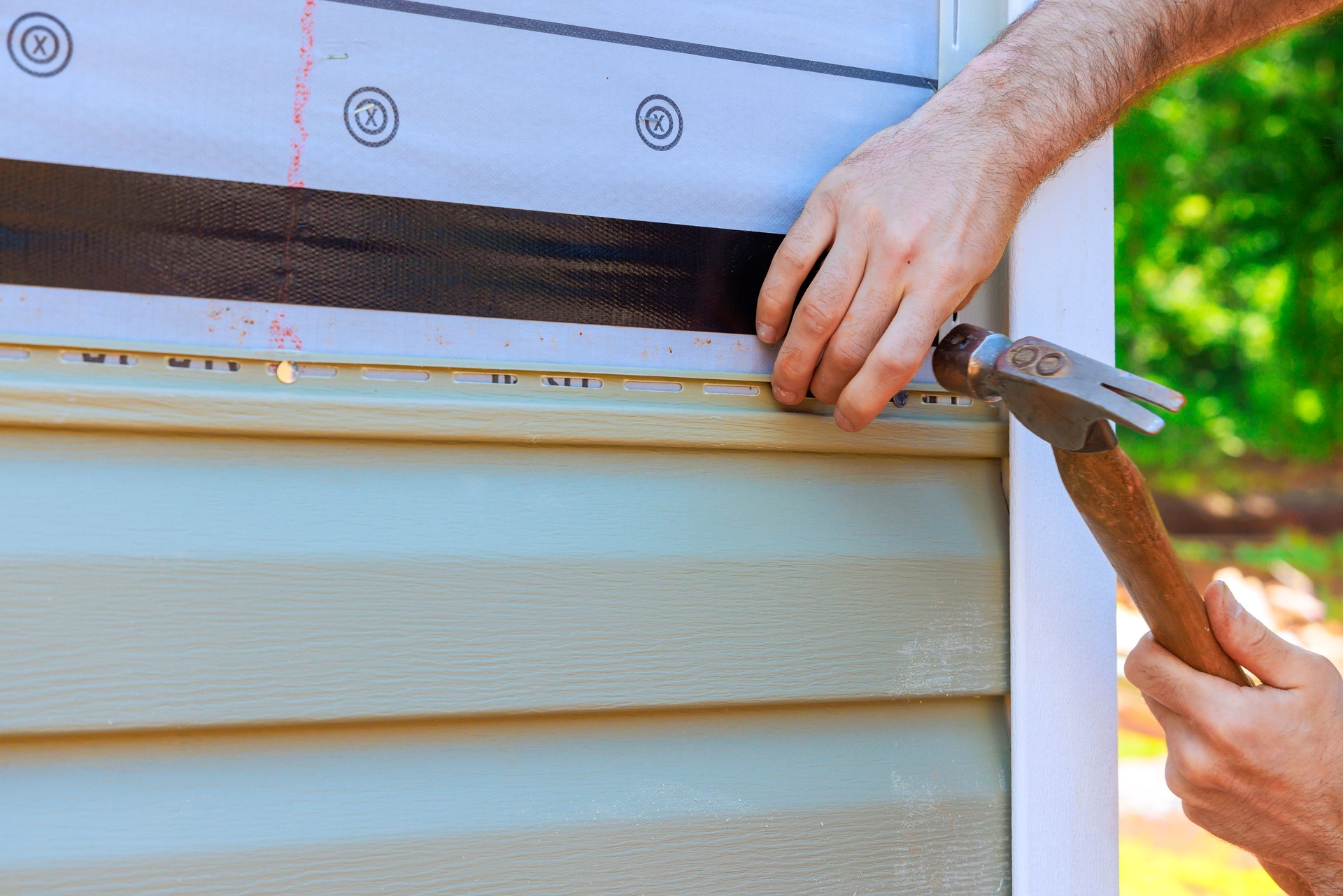 Homeowner installing new vinyl siding on residence with focus on careful craftsmanship modern materials